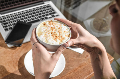 Midsection of woman holding coffee cup on table