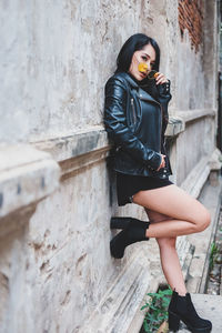 Portrait of young woman standing against wall