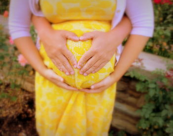 Midsection of woman holding yellow while standing outdoors