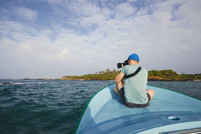 Rear view of man on boat in sea against sky