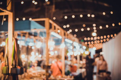 Defocused image of people at illuminated market during night