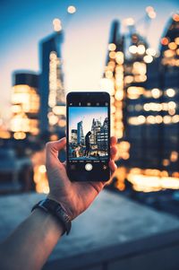 Midsection of person photographing illuminated smart phone in city