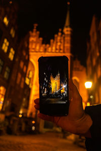 Tourist taking photo on mobile phone of cityscape of gdansk with st. mary basilica and city hall at