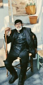 Full length portrait of smiling man sitting in hat