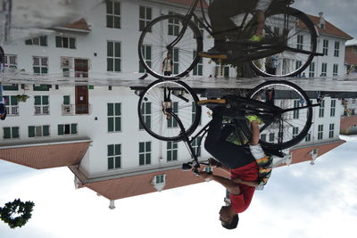 Full length of man on bicycle by building in city