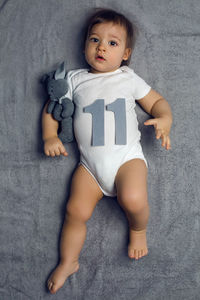 Newborn baby lying on bed with figures of his age eleven months