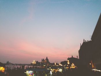 Illuminated buildings against sky at dusk