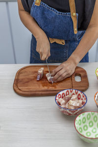 Vertical shot of a woman in the kitchen cutting meat for dinner