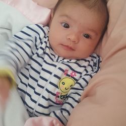 Portrait of cute baby lying on bed at home