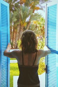 Rear view of woman standing by window