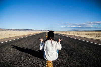 Rear view of woman sitting on road