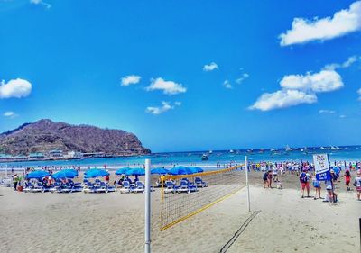 People on beach against blue sky