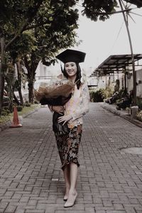 Portrait of smiling young woman standing on footpath