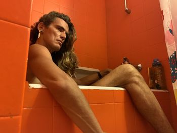 Young woman sitting in bathroom at home