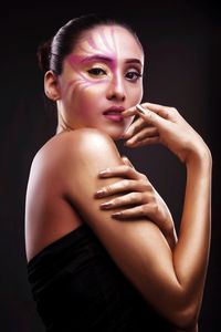 Portrait of young woman against black background