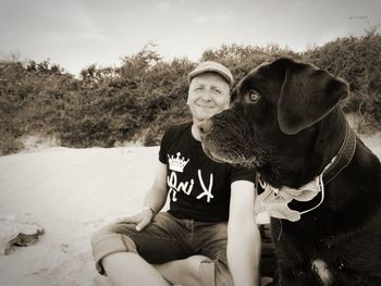 Young man with dog sitting on land