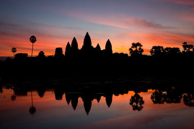 Scenic view of temple silhouette on water at sunset