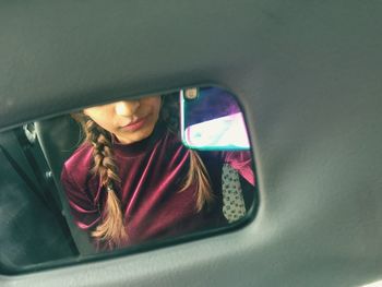 Reflection of woman in mirror of car