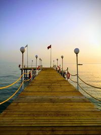 Pier over sea against sky during sunset