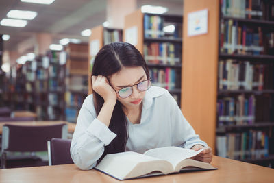 Young woman reading book at library