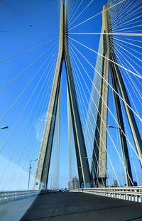 Low angle view of suspension bridge against blue sky