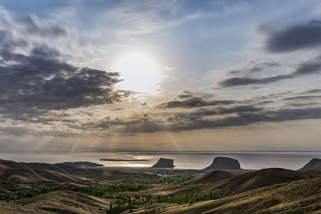 SCENIC VIEW OF SUN SHINING THROUGH CLOUDS OVER LAND