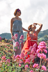 Two young hippie women sitting embraced on the lava rock on hillside of etna.