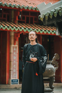 Portrait of young woman standing against temple