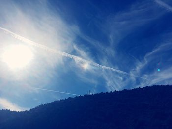 Low angle view of vapor trail against blue sky on sunny day