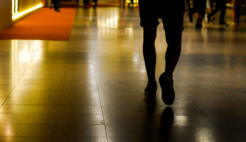 Low section of man walking on tiled floor