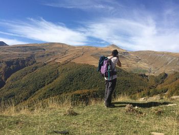 Rear view of man standing on mountain against sky