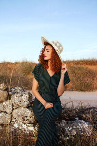 Portrait of beautiful young woman standing against sky