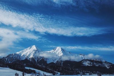 Snow covered mountains against cloudy sky