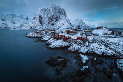 Scenic view of snowcapped mountains by sea against cloud sky