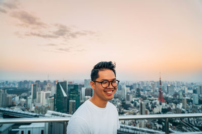 Smiling man standing at observation point against tokyo tower in city