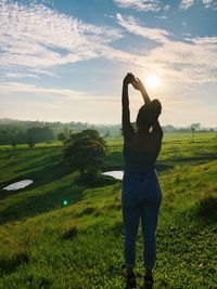 Rear view of woman standing on field against sky