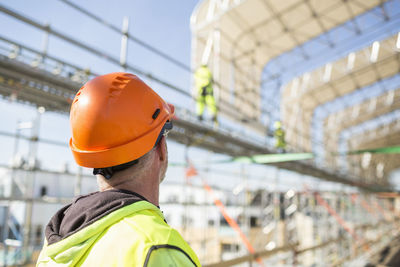 Rear view of worker looking at colleagues working at construction site