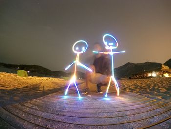 Digital composite image of man and light trails on street at night