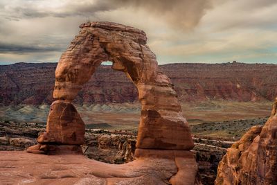 Rock formations on landscape against cloudy sky