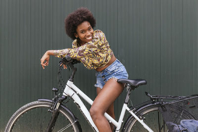 Beautiful woman leaning on bicycle by wall