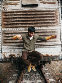Portrait of young man sitting on railroad track