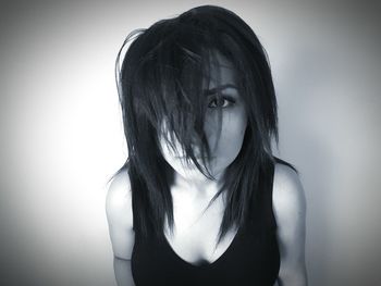 Portrait of young woman with messy hair standing against white background