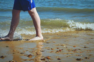 Low section of man standing on beach