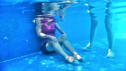 Low section of man swimming in pool