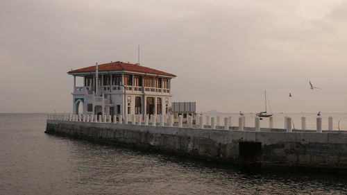 Building by sea against sky during sunset