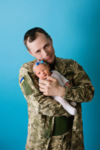 High angle view of boy with arms raised against blue background