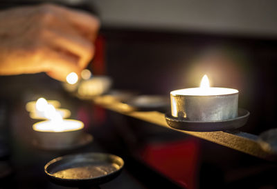 Cropped hand burning candles on table