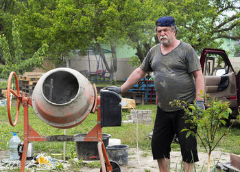 Mature caucasian man mixes cement mortar in concrete mixer