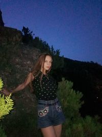 Young woman standing by tree against sky
