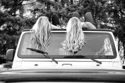 Low angle view of friends lying on car roof